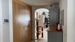 Ein Flur mit einem Holzschrank, einer Katzenkletteranlage und einer Küchenzeile.