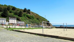 Een strandvolleybalveld met een net, een zandgebied en een gebouw op de achtergrond.
