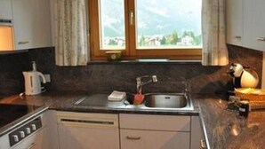 Een keuken met een raam, een spoelbak en een fornuis.
