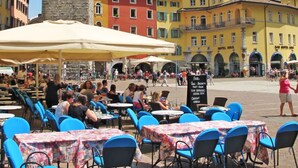 Una piazza con posti a sedere all'aperto, una torre dell'orologio e edifici colorati sullo sfondo.