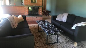 A living room with two black sofas, a patterned coffee table, a brick fireplace, and a green accent wall. - Soldanella by Interhome (Appenzell)