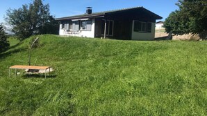 A two-story house with a sloped roof, a small attached garage, and a grassy hill in the foreground. - Soldanella by Interhome (Appenzell)
