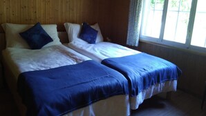 Une chambre avec deux lits, des murs en bois et une fenêtre avec des rideaux.