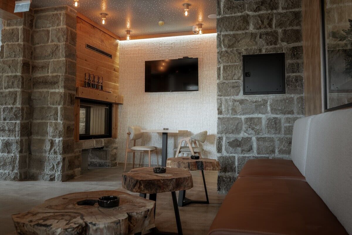 A cozy interior with stone walls, a fireplace, a TV mounted on the wall, and wooden furniture.