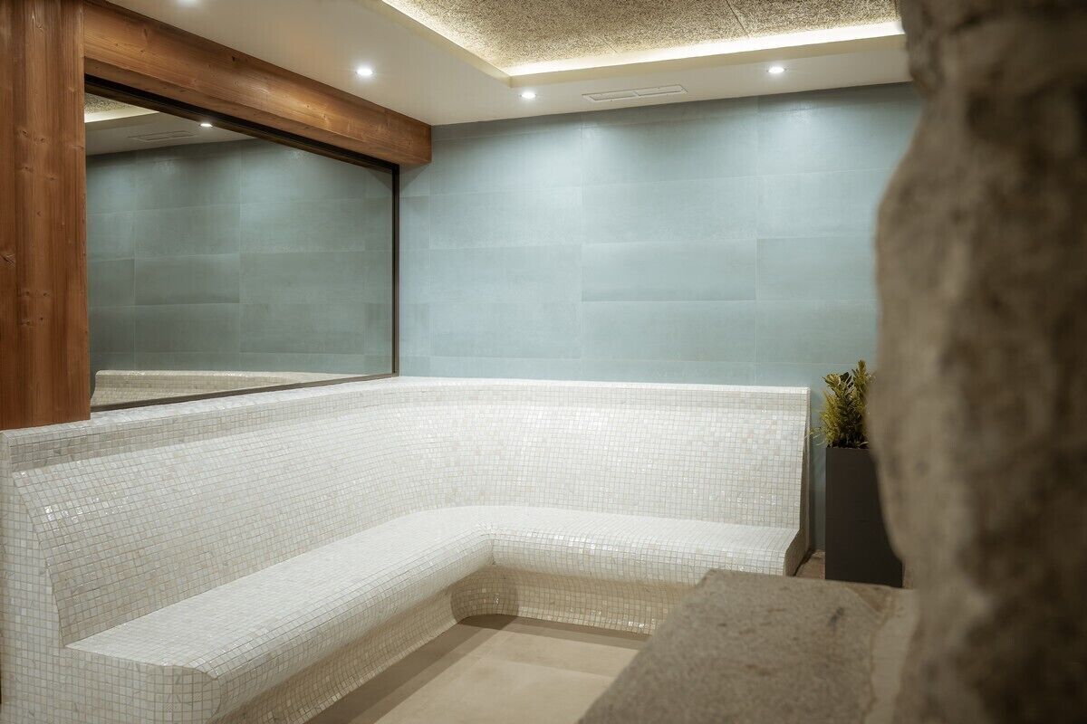 Un baño moderno con una bañera grande, paredes con azulejos y estructura de vigas de madera.