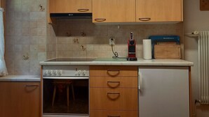 Et køkken med træskabe, indbygget ovn, bordplade med en blender og en køkkenrulleholder.