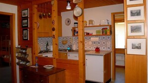 A kitchen with wooden cabinets, a white refrigerator, and a tiled backsplash. - Chalet Crystal by Interhome (Lauterbrunnen)