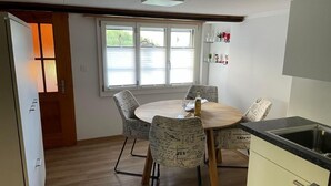 Een compacte keuken met een eethoek, met een ronde tafel, gestreepte stoelen en een ingebouwde gootsteen.