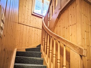 Eine Holztreppe mit einer gebogenen Handläufe und einem Fenster darüber.