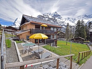 A wooden chalet with a balcony, outdoor seating, and a mountain backdrop. - Apartment West by Interhome (Lauterbrunnen)