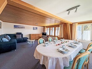 Een eetruimte met een ronde tafel voor vier personen, omringd door stoelen.