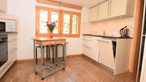Cucina moderna con mobili in legno, lavello in acciaio inossidabile e forno a microonde sul piano di lavoro.