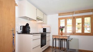 Una cucina compatta con mobili bianchi, un forno a microonde, una macchina da caffè e un termosifone.