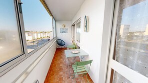 A narrow balcony with a table and chairs, a view of the street, and a small garden area. - Air Marin - Apartment with a Balcony and Ocean View (Saint-Hilaire-de-Riez)