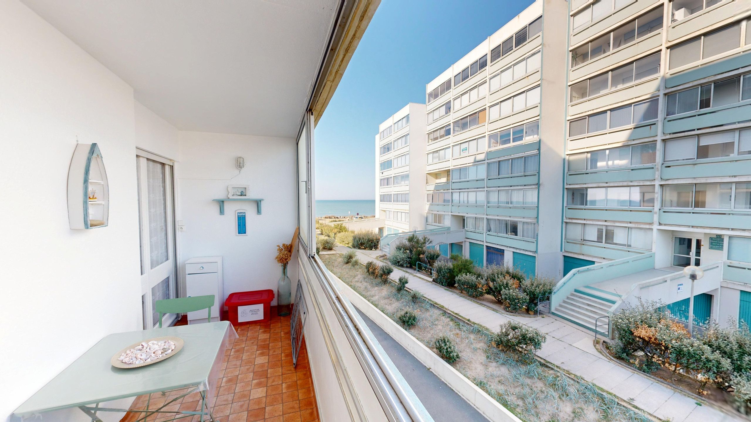 Ein Balkon mit Tisch, Stuhl und einer kleinen Ablage mit Dekoration.