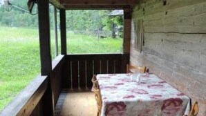 A wooden deck with a table and chairs, covered by a floral tablecloth. - Lengwald "Hiisli" by Interhome (Lauterbrunnen)