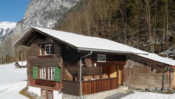 A wooden chalet with a sloped roof, a stone foundation, and a wooden porch. - Lengwald "Hiisli" by Interhome (Lauterbrunnen)
