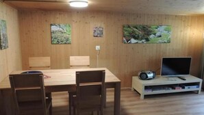A wooden-paneled room with a dining table, chairs, a TV, and a speaker. - Lengwald "Hiisli" by Interhome (Lauterbrunnen)