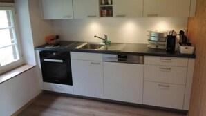 A kitchen with white cabinets, a dishwasher, and a sink. - Lengwald "Hiisli" by Interhome (Lauterbrunnen)