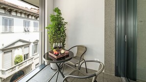 A balcony with a table, chairs, a potted plant, and a view of buildings. - Cicerone Wohnung by Interhome (Bergamo)