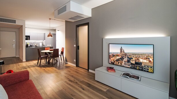 A modern living room with a flat-screen TV, a dining area, and a kitchen. - Cicerone Wohnung by Interhome (Bergamo)