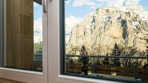 A mountain view from a window with a wooden bench and a bottle of wine. - Chalet Raufthubel by Interhome (Lauterbrunnen)