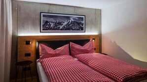A bedroom with a bed, a chair, a framed picture on the wall, and a wooden headboard. - Chalet Raufthubel by Interhome (Lauterbrunnen)