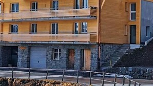 A multi-story wooden building with balconies, a stone base, and a flag on top. - Chalet Raufthubel by Interhome (Lauterbrunnen)
