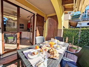 Zona d'esmorzar a l'aire lliure amb taula preparada, plats amb menjar, begudes i varietat de fruites.