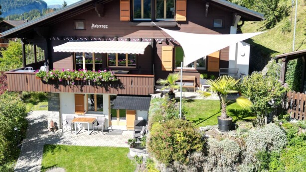 Una cabaña con zona de patio, mobiliario exterior y vistas de las montañas circundantes.