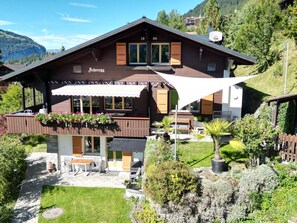 Un chalet con un patio, posti a sedere all'aperto e vista sulle montagne circostanti.