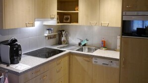 Una cocina moderna con armarios de madera, horno empotrado, lavavajillas y cafetera.