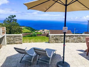 An outdoor seating area with a table and chairs, a large umbrella, and a view of the sea. - Casabelavista III by Interhome (Algarvia)