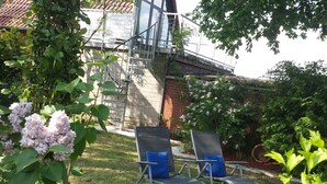 Een tuin met twee loungestoelen en een trap naar een gebouw.