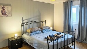 A bedroom with a bed, nightstand, and a wall-mounted lamp. - Charmantes Ferienhaus mit schöner Aussicht, 2 Sc by Interhome (Aljezur)