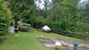 Une zone herbeuse avec un petit étang, une clôture en bois et une table de pique-nique couverte.