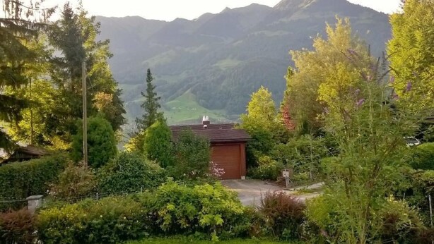 Un paysage de montagne avec un petit bâtiment entouré d’une végétation luxuriante et d’arbres.