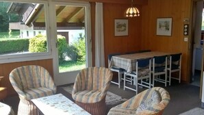 Une pièce chaleureuse, meublée de meubles en osier, avec une table à manger et une vue sur l’extérieur.