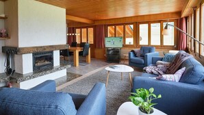 Ein gemütliches Wohnzimmer mit Kamin, Fernseher und bequemen Sitzgelegenheiten.