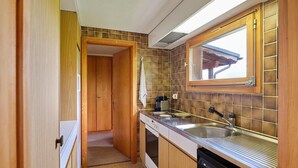 Eine kleine Küche mit Holzausstattung, einem integrierten Geschirrspüler und einem Fenster über der Spüle.