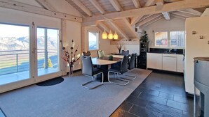 A modern kitchen with a dining area, large windows, and a view of the mountains. - Flumserberg by Interhome (Flumserberg Tannenheim)