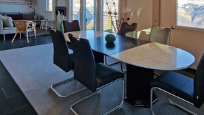 A modern interior with a large round table, black chairs, and hanging pendant lights. - Flumserberg by Interhome (Flumserberg Tannenheim)