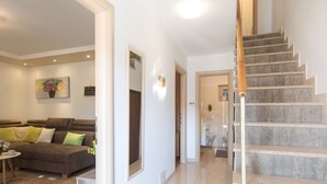 Un saló modern amb un sofà marró, una taula de centre i un quadre a la paret. Una escala condueix a un bany amb vàter i rentamans.