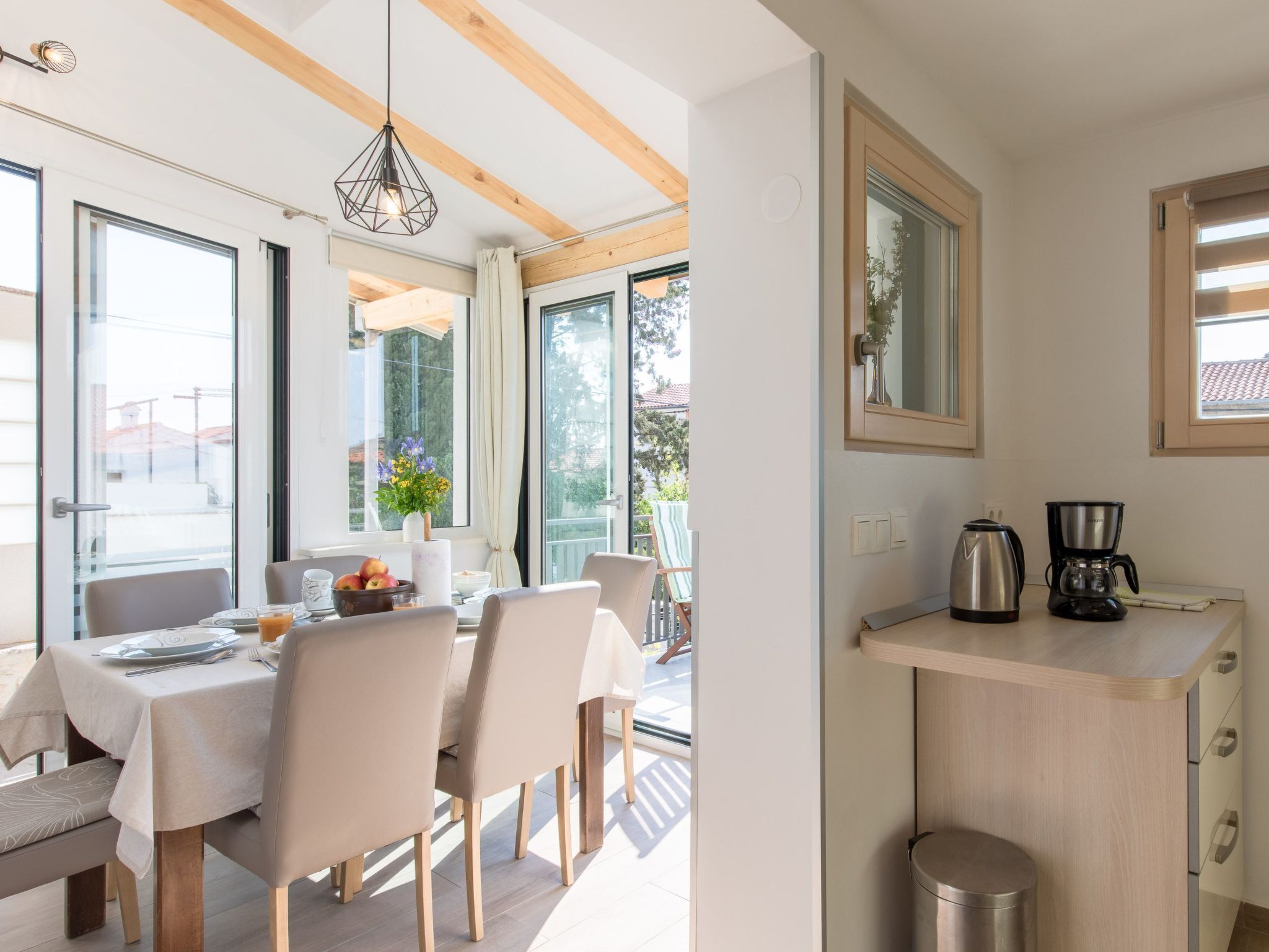 A modern kitchen with a built-in coffee maker, a small sink, and a window overlooking a balcony.
