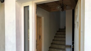 A staircase leading to an upper floor, with a wooden door and a small wicker chair at the bottom. - Ferienvilla mit Terrasse, Grill und Garten by Interhome (Karlstejn)