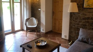 A living room with a wicker chair, a coffee table with a remote control, a lamp, and a stone wall. - Ferienvilla mit Terrasse, Grill und Garten by Interhome (Karlstejn)