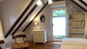 A bedroom with a wooden floor, a bed, a dresser, a chair, and a bookshelf. - Ferienvilla mit Terrasse, Grill und Garten by Interhome (Karlstejn)