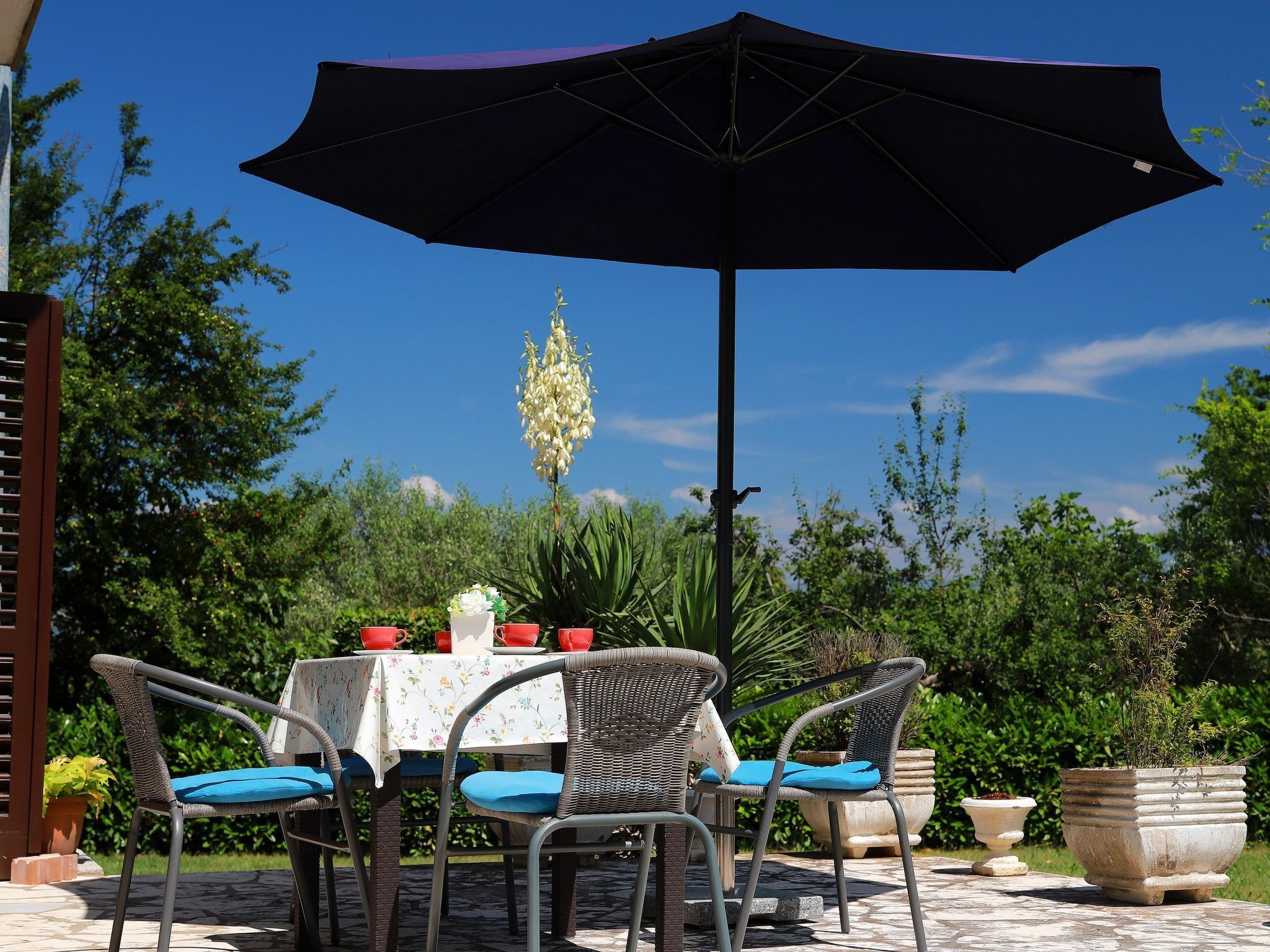 An outdoor patio with a table, chairs, and a large umbrella.
