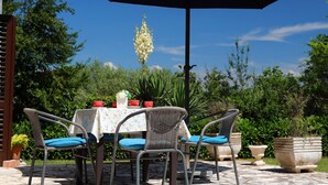 Eine Terrasse im Freien mit Tisch, Stühlen und einem großen Sonnenschirm.
