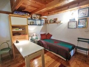 A small, cozy room with a bed, a desk, a chair, and shelves with various items. - "Das Haus des Lichts by Interhome (Nus)